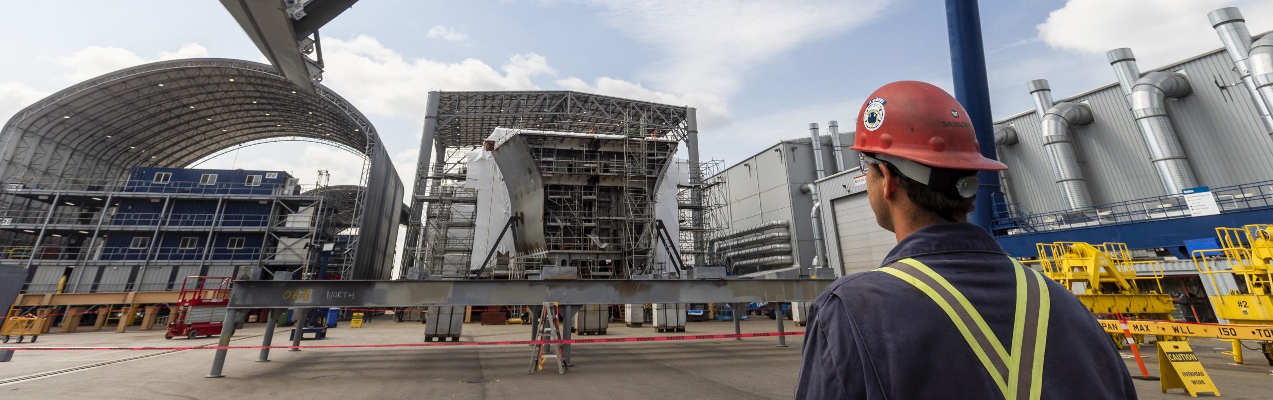 man looking at ship under construction