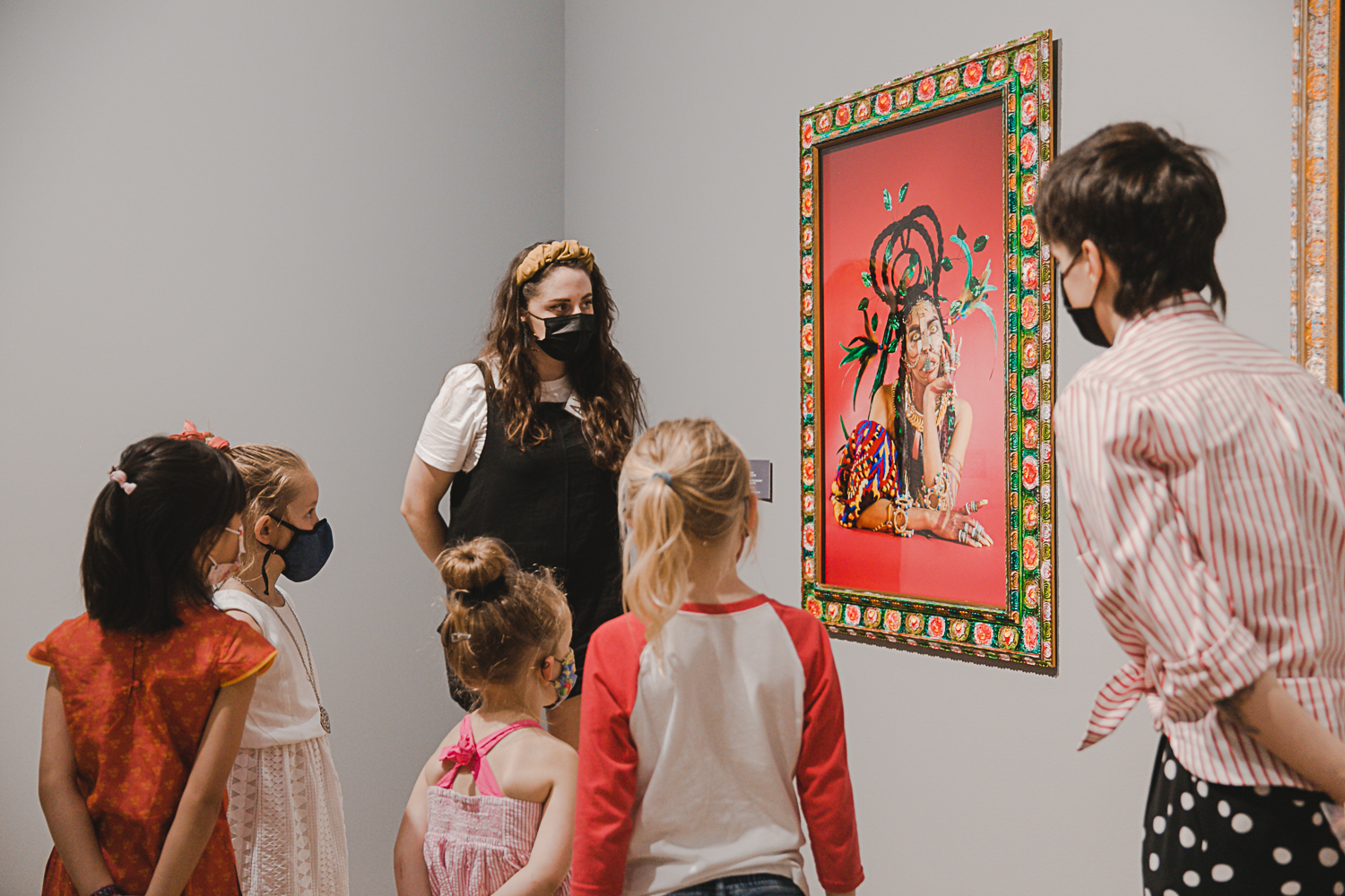 adults and children looking at piece of art on the wall