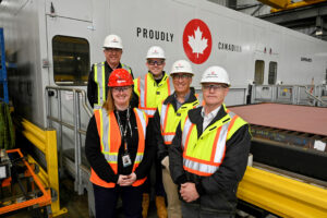 group of people standing in front of wall which reads 'proudly canadian'