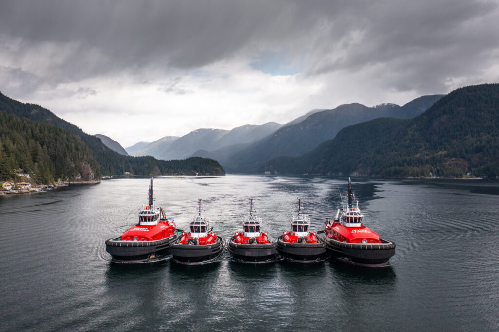 A photo of five tugboats sailing together