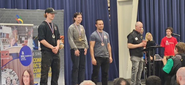 three apprentices standing on podium