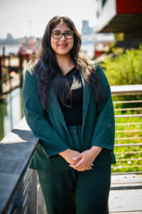A woman stands on a balcony overlooking the water