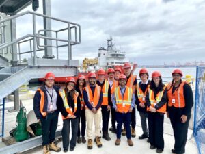 A group of interns standing on a dock in front of a red and white Coast Guard ship