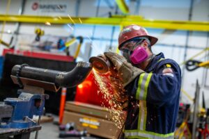 person grinding pipe spool