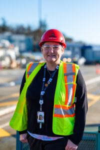 Woman in red hard hat, safety glasses, and high viz vest
