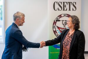 Tony Winter shakes hand with CSETS representative in front of a CSETS banner
