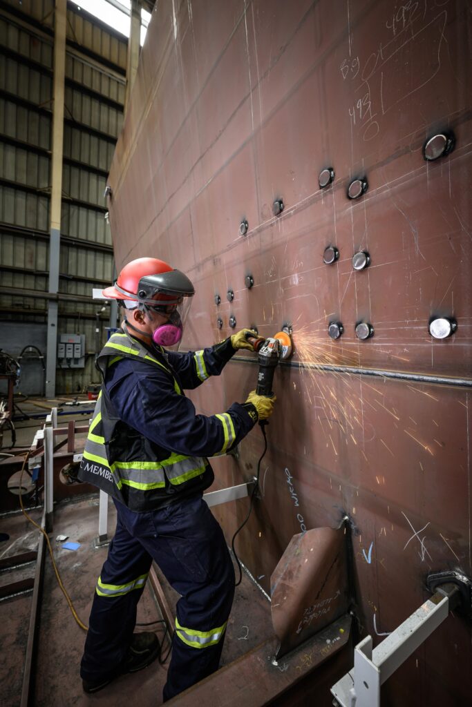 Photos of Felix Yumul, Steel Fabricator, in front of a block of red steel