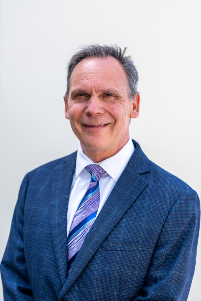 Photo of man with short hair, blue suit, purple striped tie